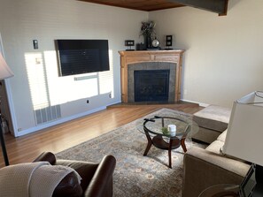 Nicely decorated sunlit living room with Smart TV, wood ceiling, and floors