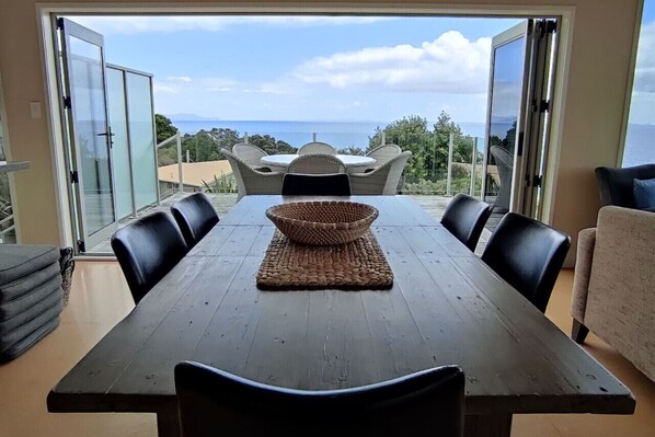 Dinning Table Looking Out of Open Bifold Doors to Outdoor Dinning Table and Deck