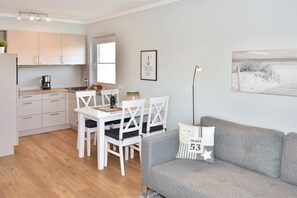 Wohnzimmer mit Couch, Essplatz und offener Küchenzeile