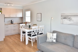 Wohnzimmer mit Couch, Essplatz und offener Küchenzeile