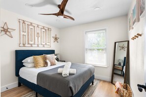 Bedroom that is set up with a cozy bed and a cool fan. Ready to relax in style?