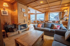 The living room with sofa area around the fireplace and large TV