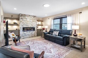 Main Living Room with Cozy Reclining Sofa, Electric Fireplace and 55" Smart TV.