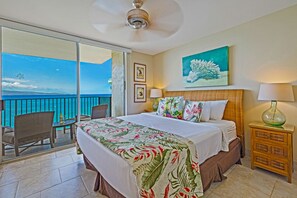 Drift to sleep with the soothing sound of ocean waves. This master bedroom features a plush king bed, tropical decor, and private lanai access with panoramic views.