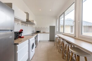 Un salon avec cuisine ouverte dans l'appartement principal pouvant accueillir 8 personnes pour dîner (10 si utilisation de la rallonge de la table) et 4 personnes sur le mange debout.