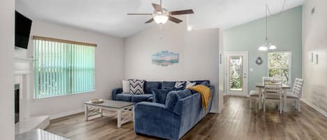 Open living room and dining room area with couch, TV, table for the kids, dining table, and a full-size pull out sleeper sofa.