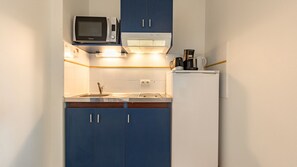 A fully equipped kitchenette featuring all the essentials, including a microwave, fridge, and stovetop.