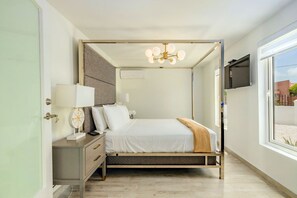 The third bedroom features a grand headboard, a beautiful fixture, a large window, a television, and a split-type air-conditioner.