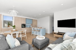 open floorplan, with high end kitchen, dining room and lounge complete with cozy couches and large smart tv and sound bar
