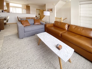 Vegan leather couch and oversized chair in living area. Desk for remote work.