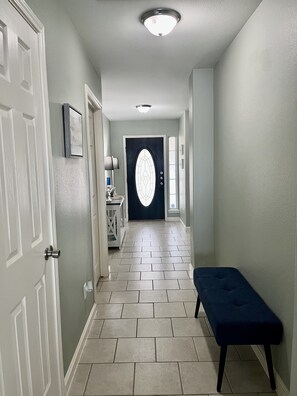 Tiled entry with accent table and coastal decor throughout home. 