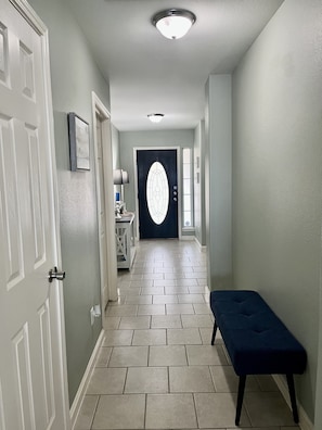 Tiled entry with accent table and coastal decor throughout home. 