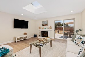 Wonderfully lit living room featuring a sky light & entrance to backyard