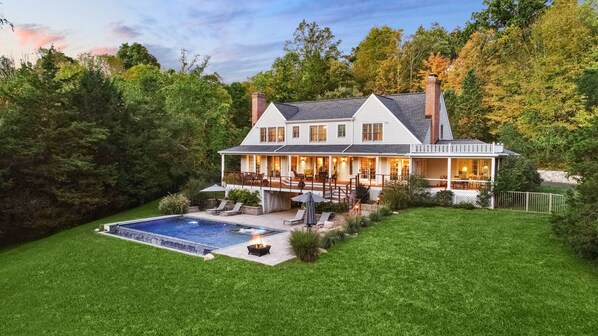 Back of the house, showing wrap around deck, infinity edge pool and hot tub