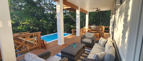 Outdoor space includes pool, lots of seating, gas BBQ and shower beneath a tree.