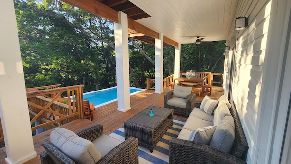 Outdoor space includes pool, lots of seating, gas BBQ and shower beneath a tree.