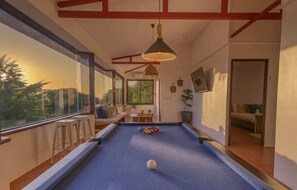 Experience fun and relaxation in this beautiful game room with panoramic views! Enjoy a game of pool as the sun sets, filling the room with a warm glow. Comfortable seating, modern decor, and large windows create the perfect atmosphere for spending quality time with loved ones. Make your stay unforgettable with this perfect blend of entertainment and tranquility.