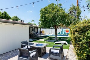 Backyard with pool, outside dining table, lounge chairs, BBQ grill, and bonfire pit.