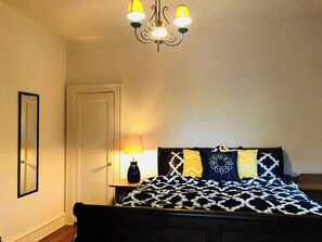 Bedroom with queen sleigh bed, chandelier, high ceilings and lots of natural light.