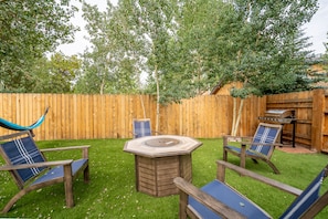 Spacious backyard with gas fire-pit, outdoor seating, hammock and gas grill.