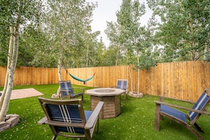 Spacious backyard with gas fire-pit, outdoor seating, hammock and gas grill.