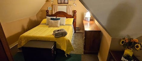 Cheery bedroom in cozy attic of centennial Queen Anne cottage. 