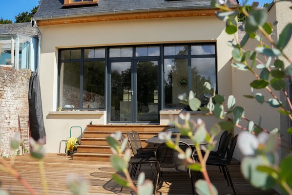 Grande terrasse en bois avec salon de jardin, BBQ et jardin engazonné