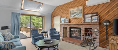 Cozy living room w/ smart tv, fireplace, split AC unit and sliding glass doors lead to wrap around porch.