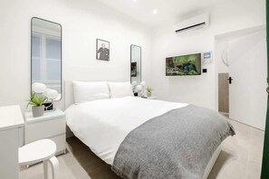 Tranquil bedroom with plush bed, Smart TV, and refreshing air conditioning.
