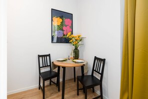 A small dining area with a round table, two chairs, and a vase of flowers, creating a comfortable nook for meals.
