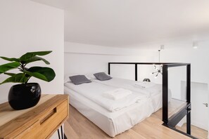 A cozy loft bed with wooden steps leading up to the sleeping platform. It provides a private nook while keeping the room open below.