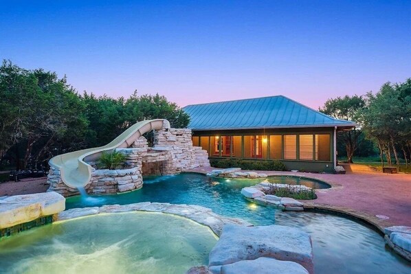 Resort style pool with hot tub, water slide and outdoor kitchen