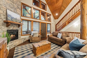 The front wall is clad with windows and a stone fireplace greets you!