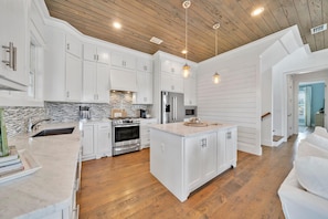 - Sleek white kitchen features stainless steel appliances and a spacious island for prepping meals or quick snacks - Beautiful backsplash and pendant lights add style and charm - Ideal for whipping up dinner or sipping morning coffee in peace