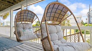 The shady lower porch features swings, chairs, and and enclosed hot/cold outdoor shower.