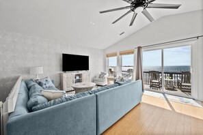 Relax after a long day at the beach in the open living area, with a large West Elm sectional, 2 swivel lounge chairs, and a large smart TV.