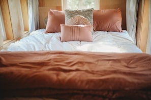 Cozy bed inside the treehouse, with soft pillows and bedding, creating a warm, inviting space.