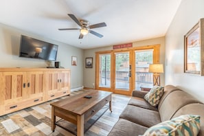 Living area featuring cozy furnishings, ceiling fan, a mounted Smart TV, and extra sleeping arrangements.