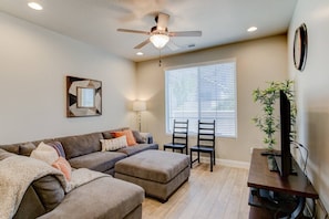 Experience the cozy living room, outfitted with plush seating, an expansive smart TV, and large windows letting in lots of light!