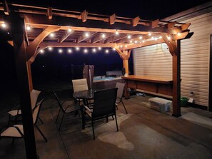 Patio with pergola, hot tub, dining set, charcoal grill, and a fire pit. 