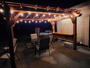 Patio with pergola, hot tub, dining set, charcoal grill, and a fire pit.