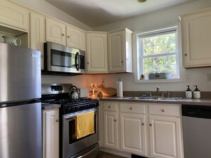 Kitchen stocked with cooking basics (salt, pepper, spices, oil). Gas stove.