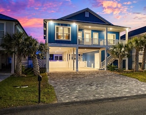 Front of the home lit up at night, welcoming you after a day at the beach.