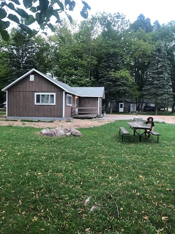 Exterior view from behind cabin showcases the picnic table and firepit