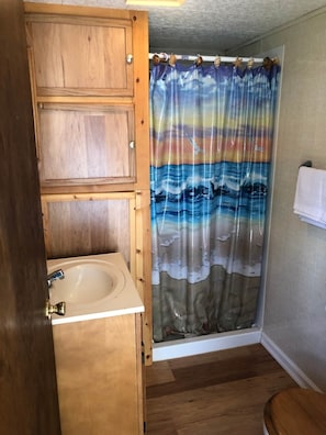 Full bathroom with stall shower, vanity, toilet and fresh linens