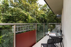 A balcony view with a small round table and two chairs, overlooking green surroundings.
