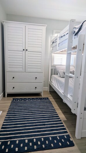 Twin over twin bedroom with armoire for hanging and storing clothes.