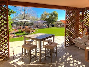 French doors in living room open to rolling grass courtyard with fire pit