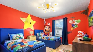 Vibrant Super Mario twin room with bold murals, star light, and playful bedding.