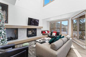 Living area featuring cozy furnishings and a wood burning fireplace with mounted TV.